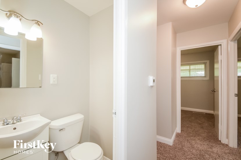 A bathroom with a toilet, sink, and mirror.