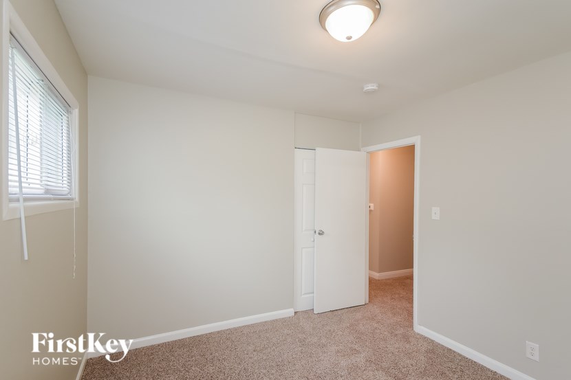 A room with a white door and a window with blinds.