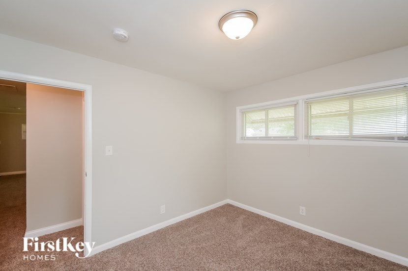 A room with a carpeted floor and a window with blinds.