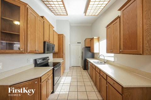 A kitchen with wooden cabinets and a tiled floor.