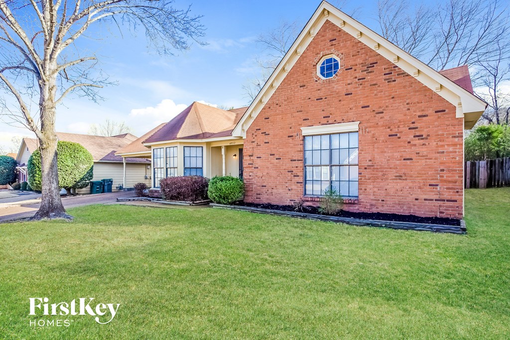 a brick house with a lawn and a tree