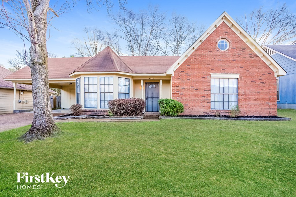 the front of a brick house with a lawn and a blue door
