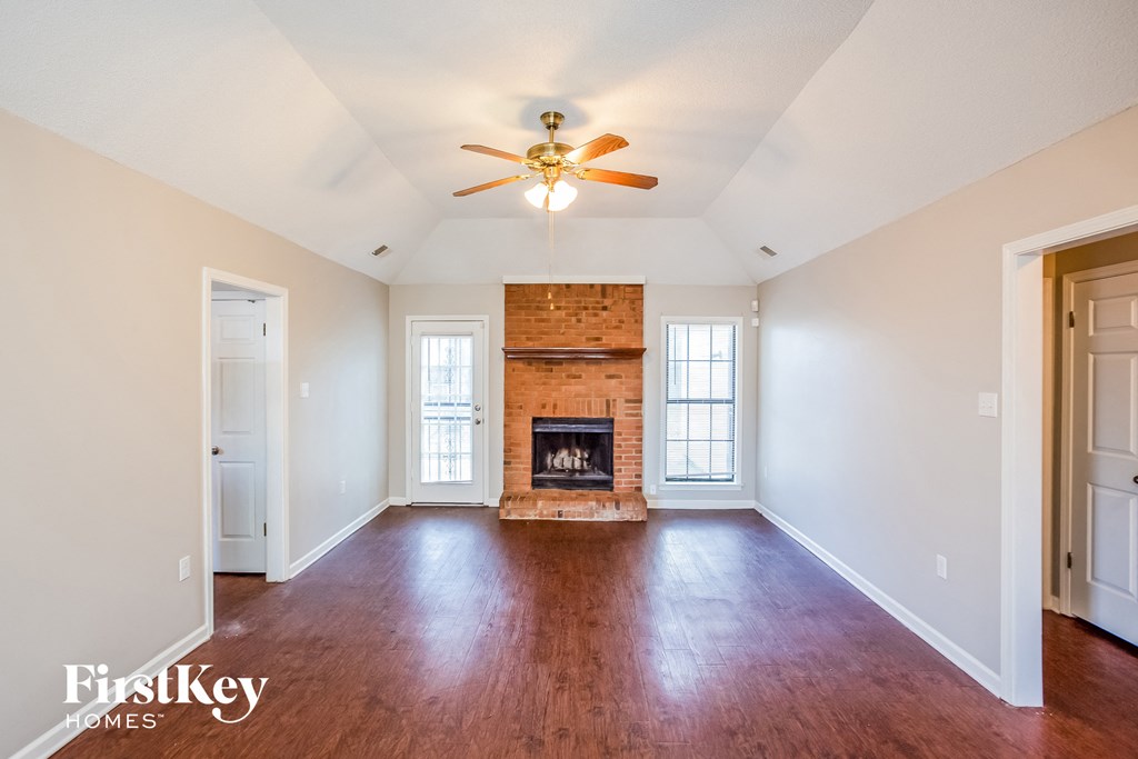 an empty living room with a fireplace and a ceiling fan