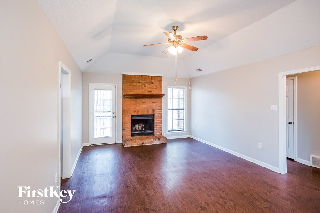 an empty living room with a fireplace and a ceiling fan