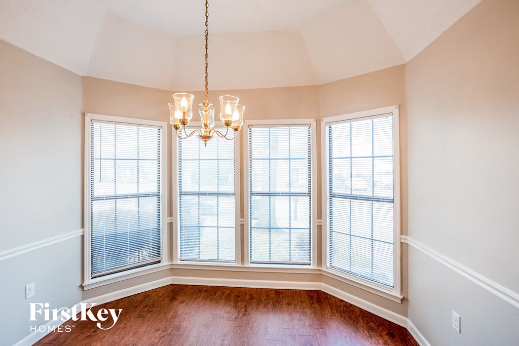 an empty living room with three windows and a chandelier