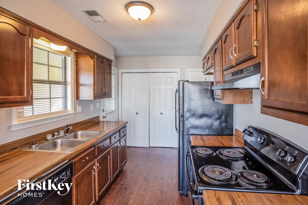 a kitchen with wooden cabinets and a black stove and refrigerator