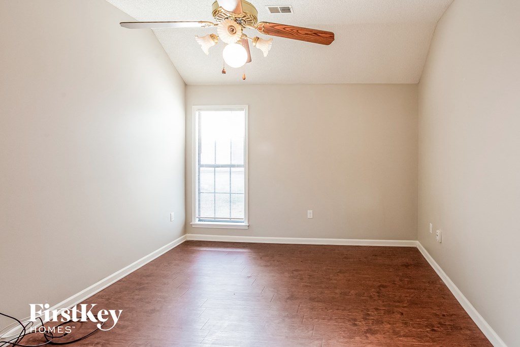 a empty living room with a ceiling fan and a window