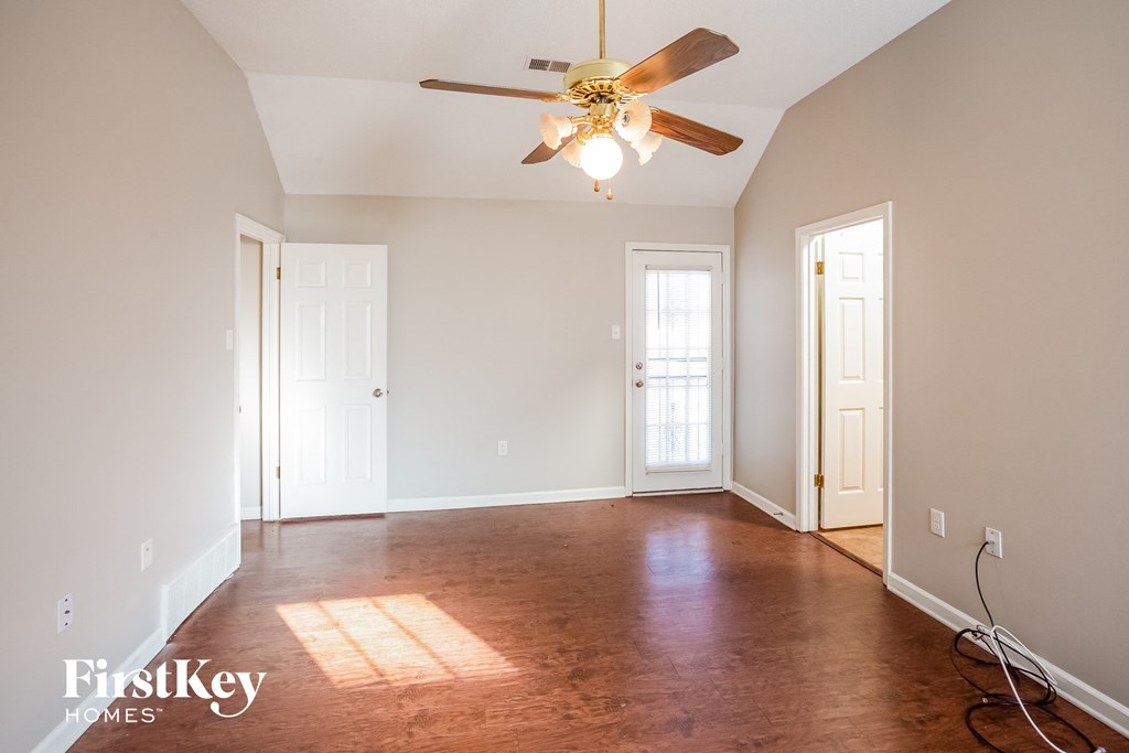 a empty living room with wood floors and a ceiling fan