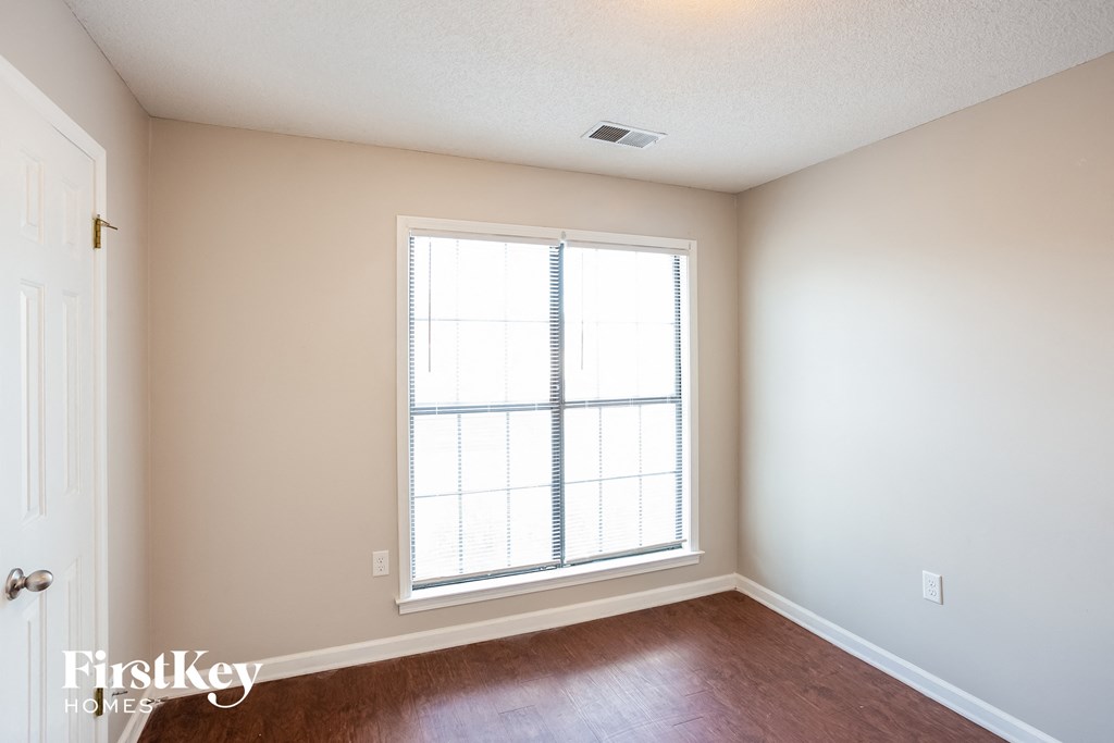 a bedroom with a large window and wooden floors