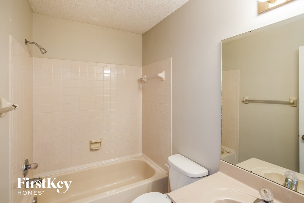 a white bathroom with a tub and a sink and a mirror