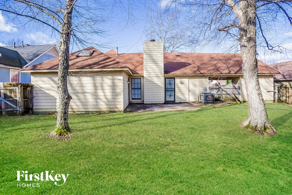 a white house with a red roof and a yard with trees