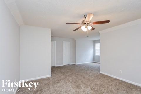 a living room with carpet and a ceiling fan