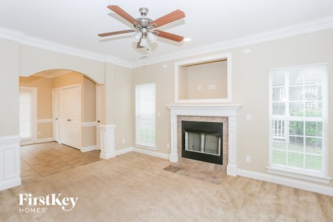 A spacious living room with a fireplace and a ceiling fan.
