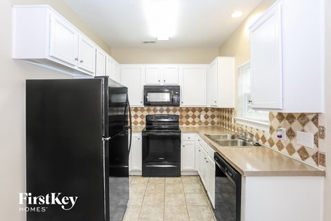 A kitchen with a black fridge and white cabinets.