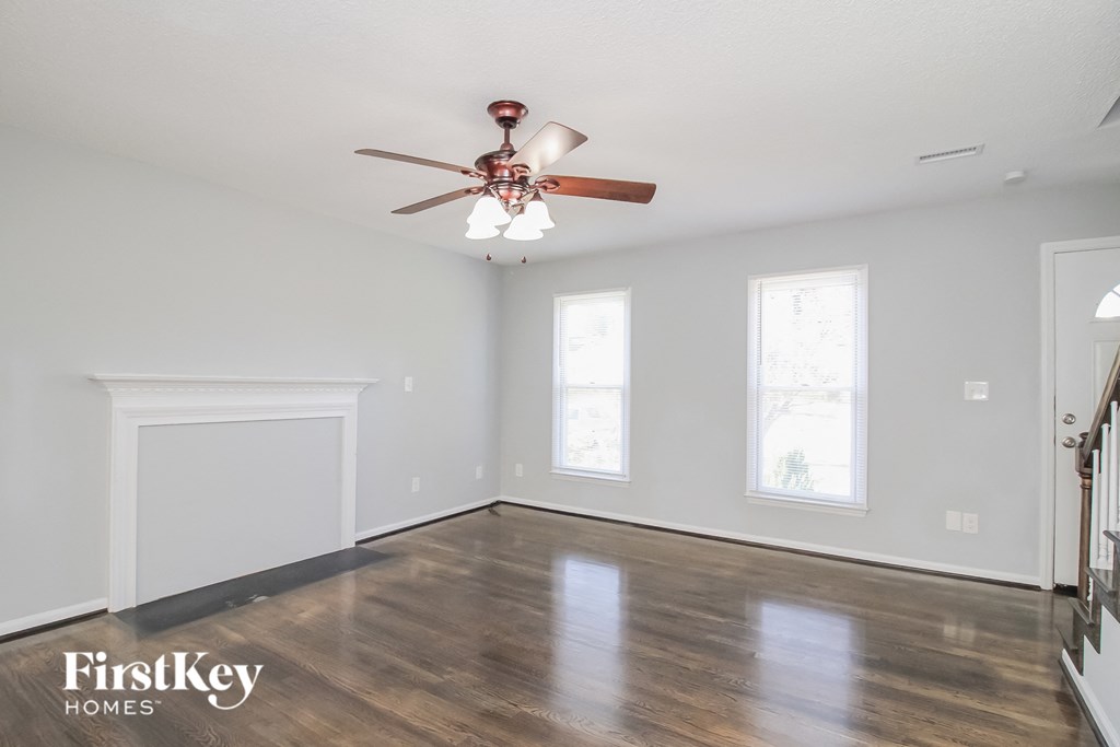 a living room with white walls and a ceiling fan