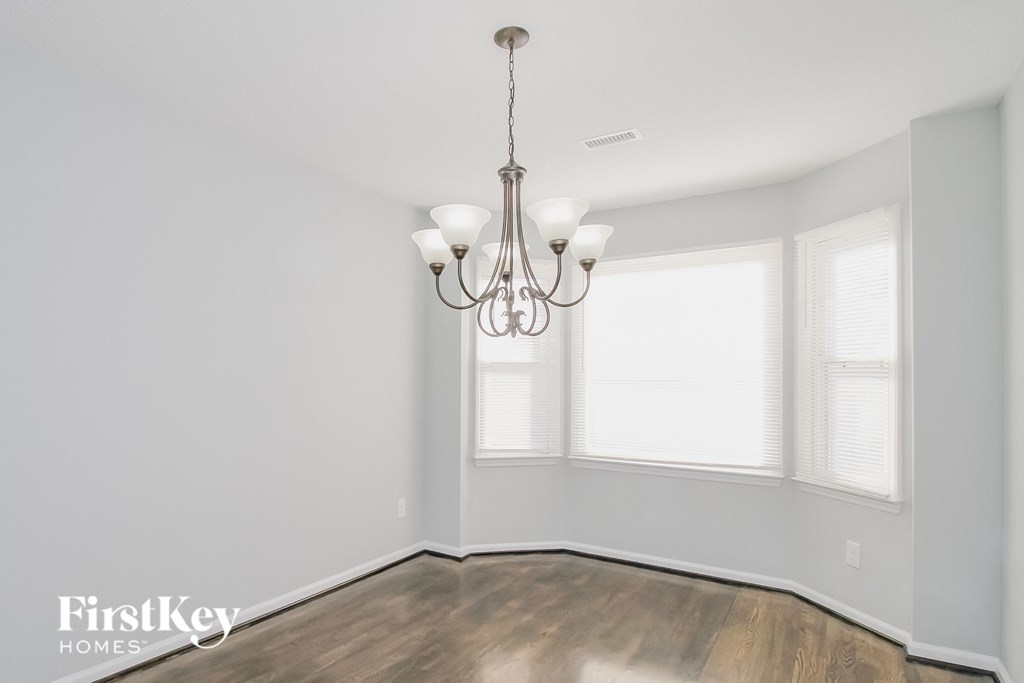 an empty room with a chandelier and two windows
