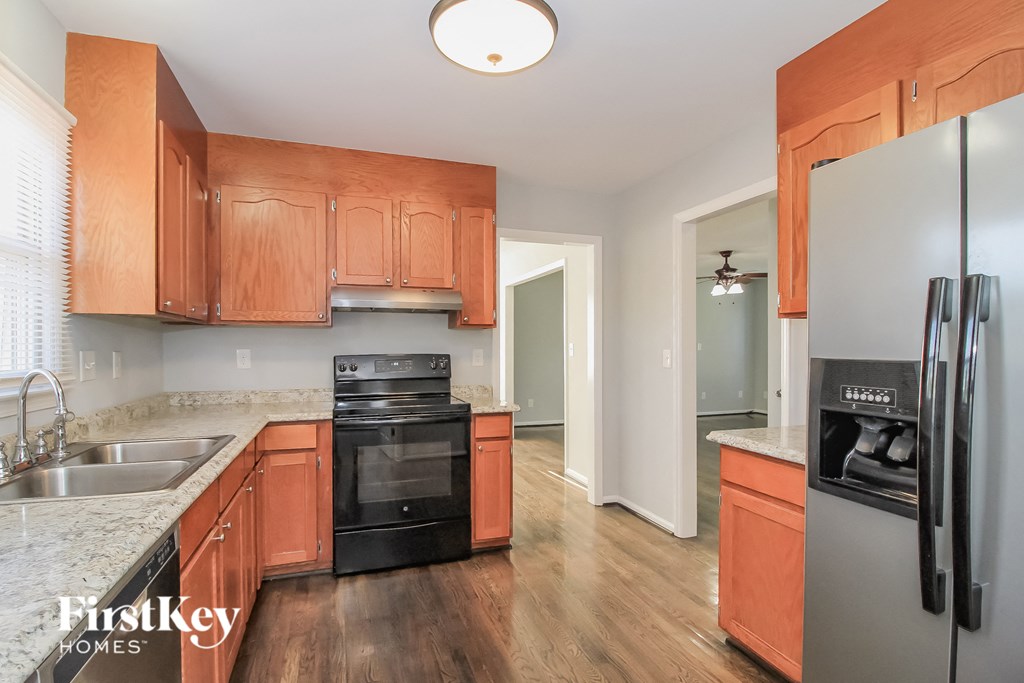 an empty kitchen with wooden cabinets and a black stove and refrigerator