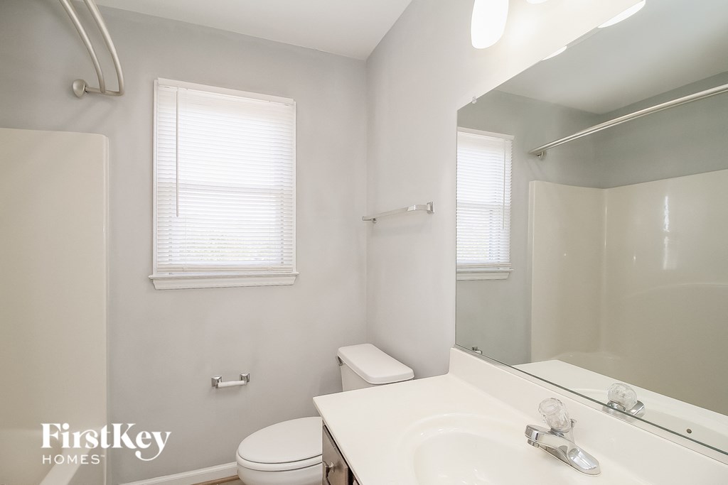 a white bathroom with a mirror and a toilet and a sink