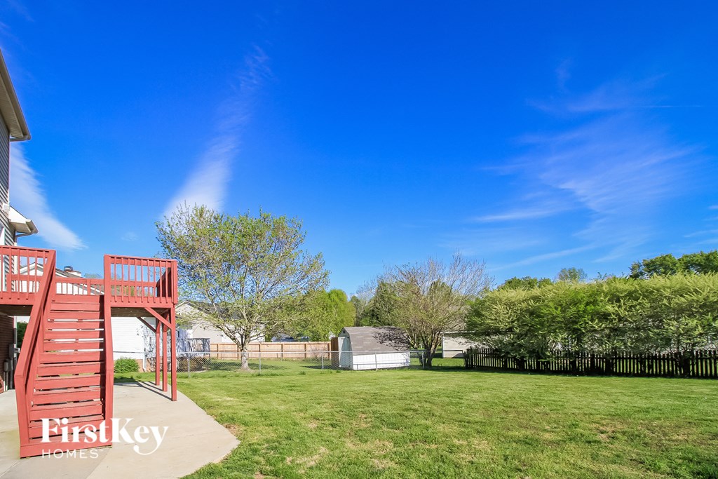 a backyard with a red ladder and a grassy field