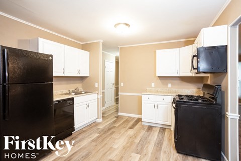 A kitchen with a black fridge and white cabinets.