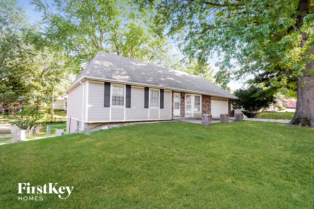 a small white house with a lawn and trees