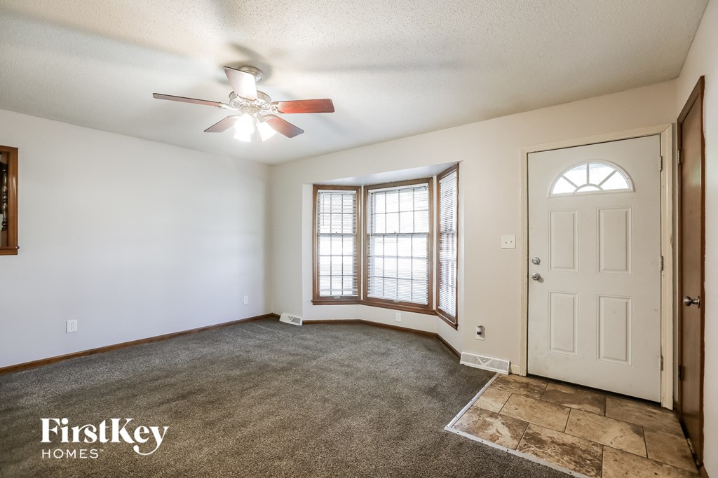 an empty living room with a white door and a ceiling fan
