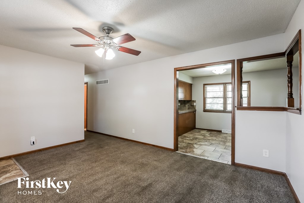 an empty living room with a ceiling fan and a door to a bathroom
