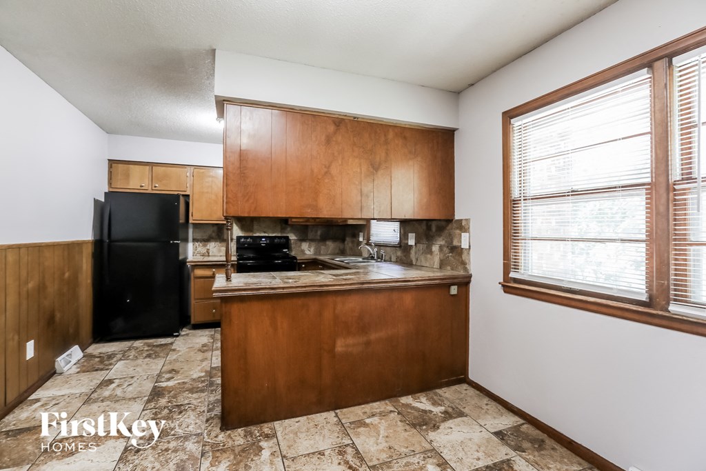 a kitchen with wood cabinets and a black refrigerator