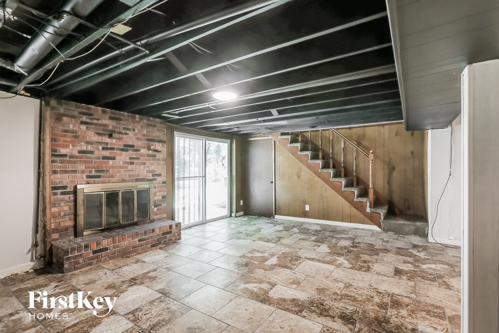 a living room with a brick fireplace and a staircase