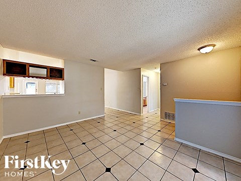 a spacious living room with tiled flooring and white walls