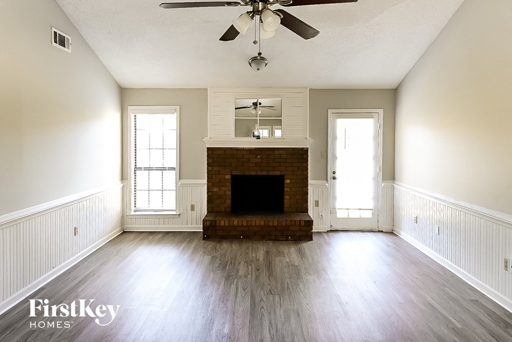 A spacious living room with a fireplace and a ceiling fan.