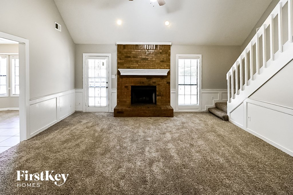 A spacious living room with a fireplace and a staircase.