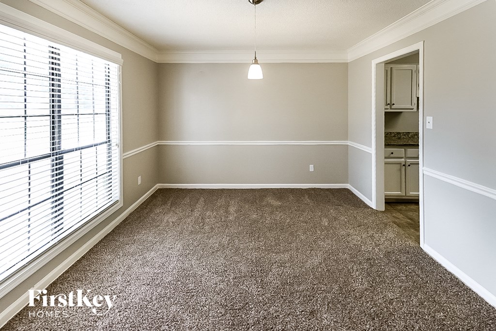 A room with a carpeted floor and a window with blinds.