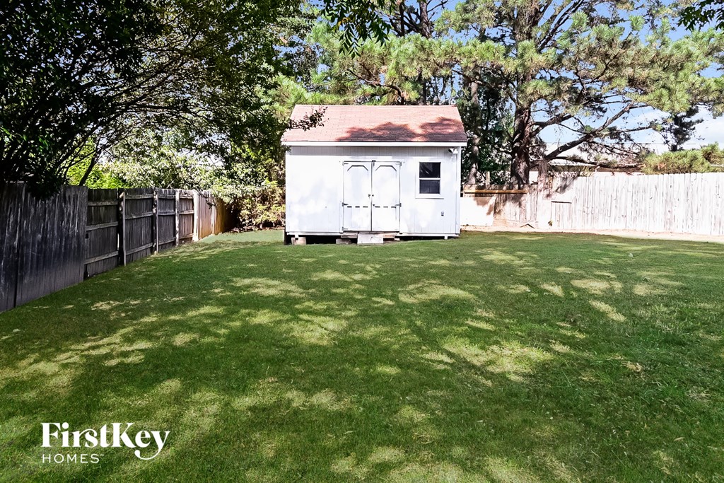 A white shed sits in a grassy backyard.