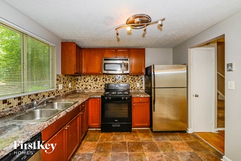 A kitchen with a black stove top oven and a stainless steel refrigerator.