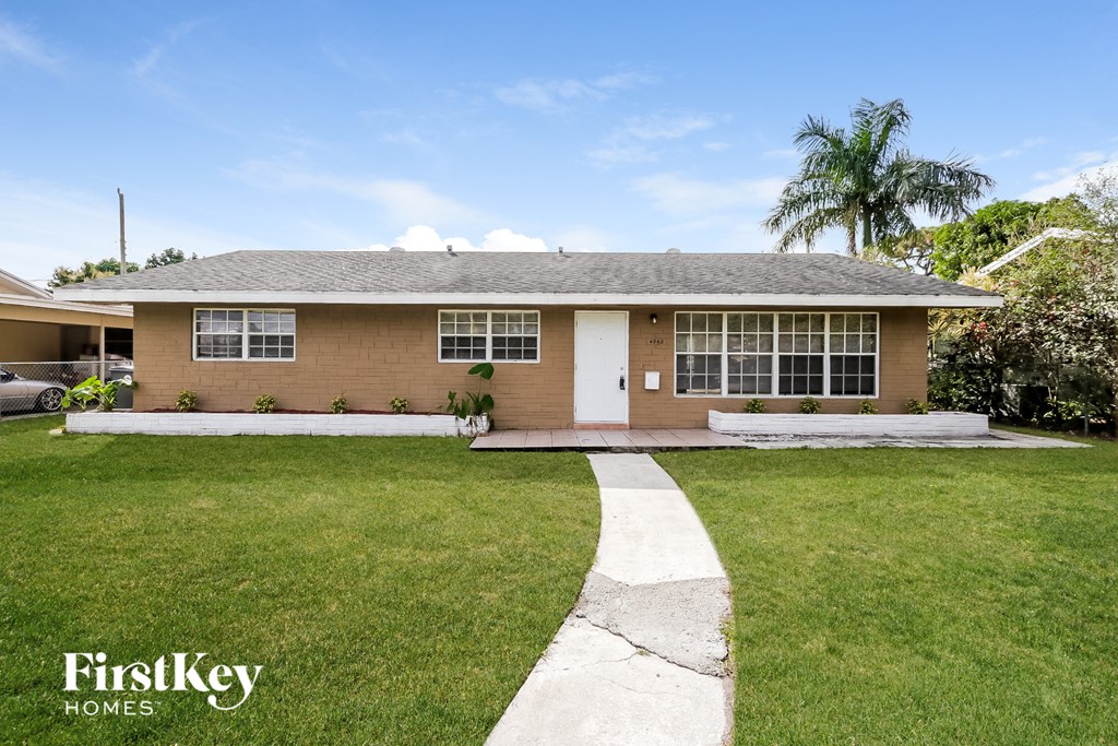 a brown house with a lawn and a palm tree