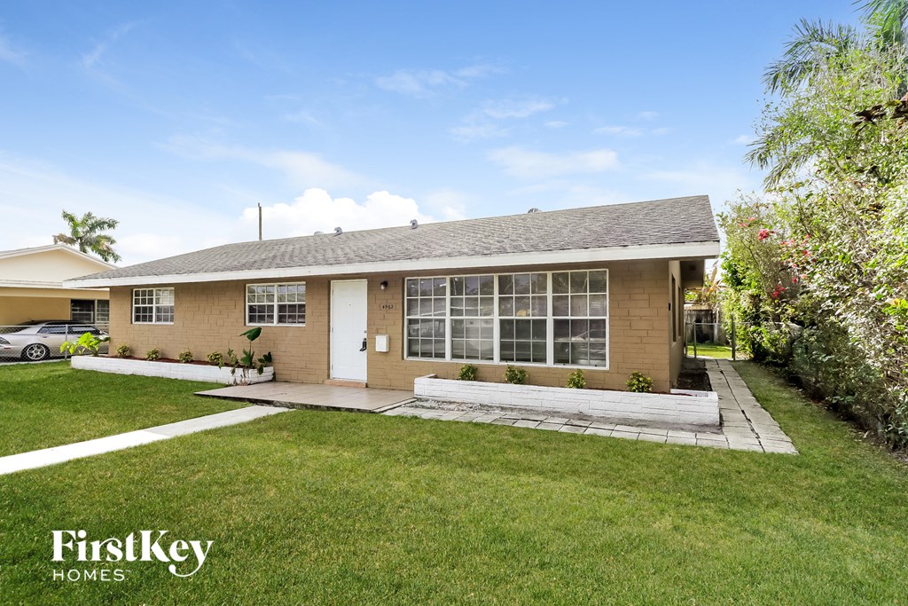 a small brown house with a lawn and a driveway