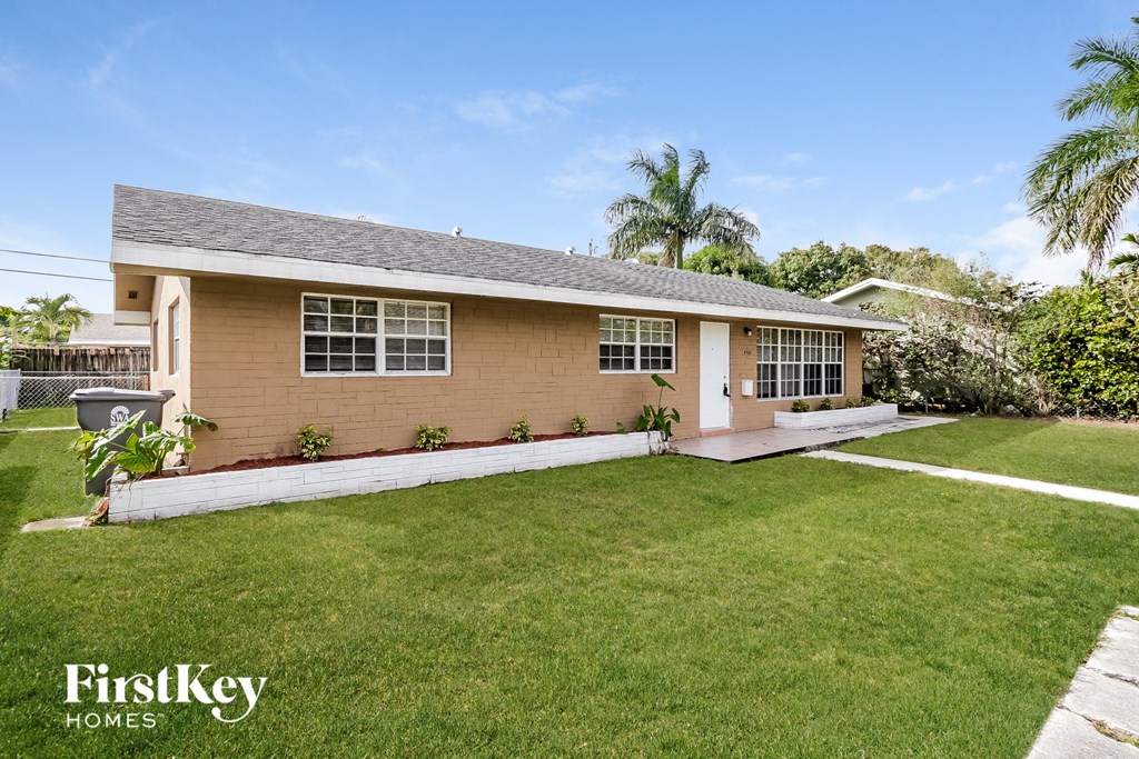 a small brown house with a lawn and palm trees