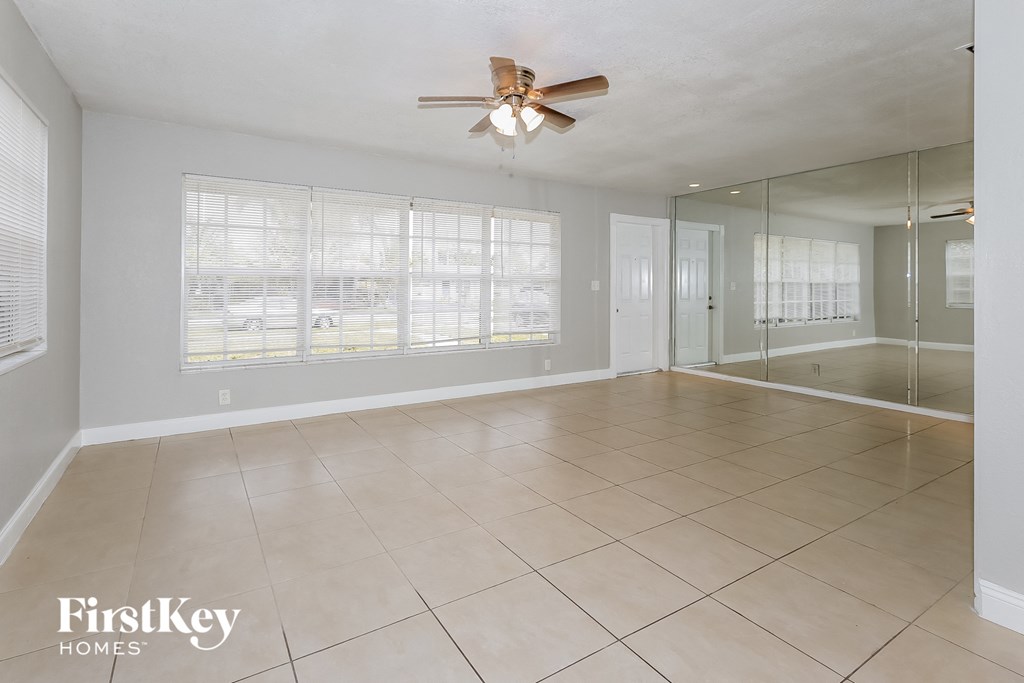 an empty living room with a ceiling fan and a large window