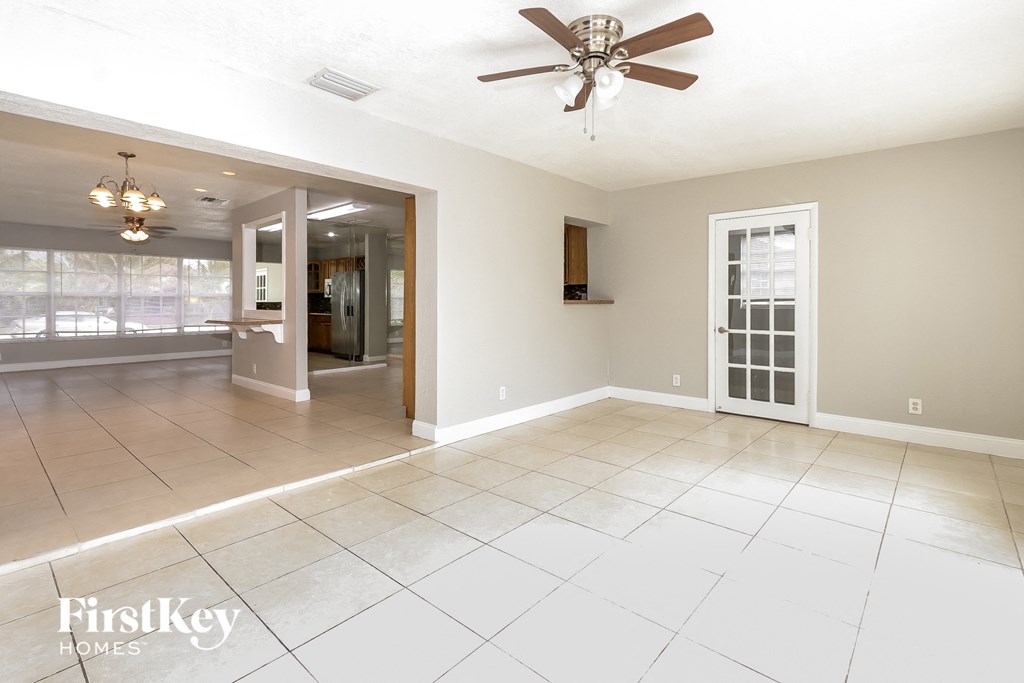 an empty living room with a ceiling fan and tiled floor