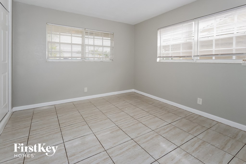 a empty room with two windows and a tiled floor