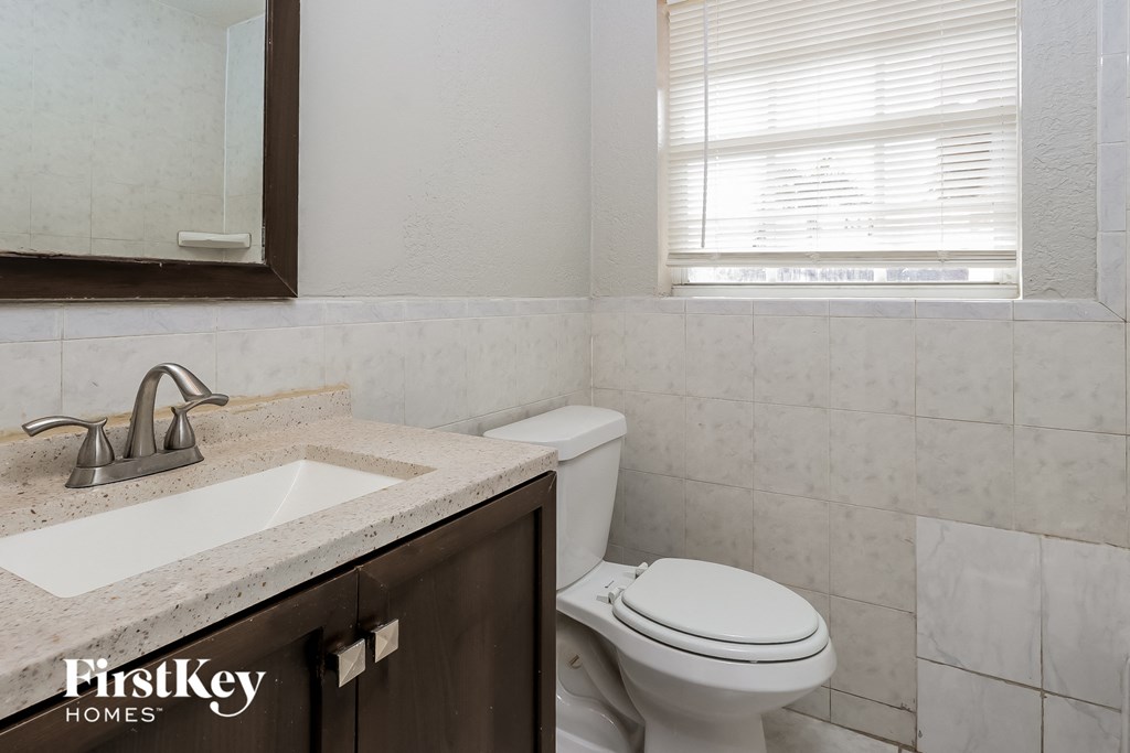 a bathroom with a toilet and a sink and a window