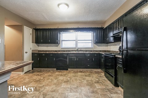 A kitchen with black cabinets and a tiled floor.