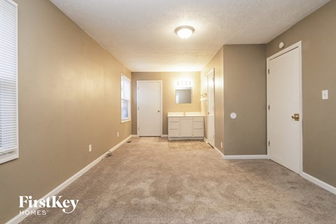 A spacious room with a carpeted floor and a mirror on the wall.