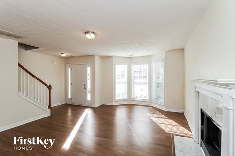 A spacious living room with wood flooring and a fireplace.
