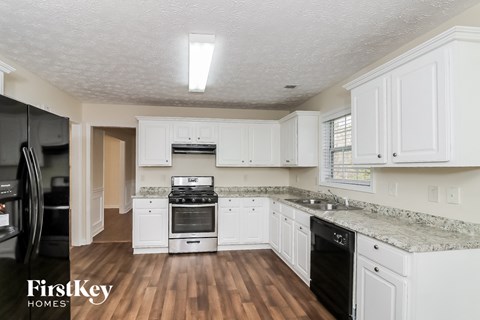 A kitchen with white cabinets and a black fridge.