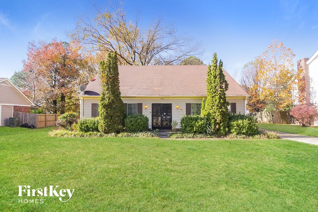 A house with a lawn in front of it and trees around it.