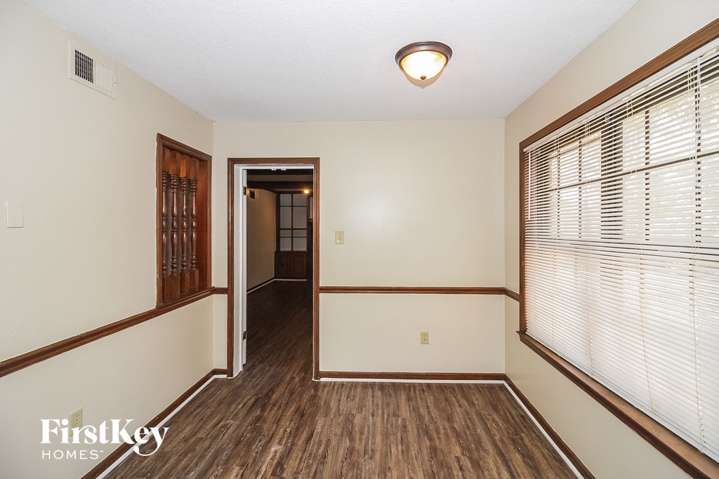A room with wooden floors and a window with blinds.
