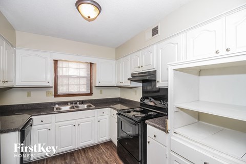A kitchen with white cabinets and a black stove top.