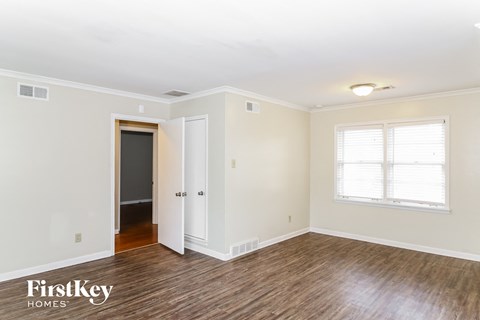 the living room of a home with a wood floor and white walls and a door